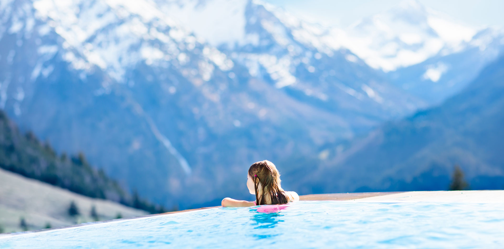 fille accoudée à une piscine sur un paysage enneigé