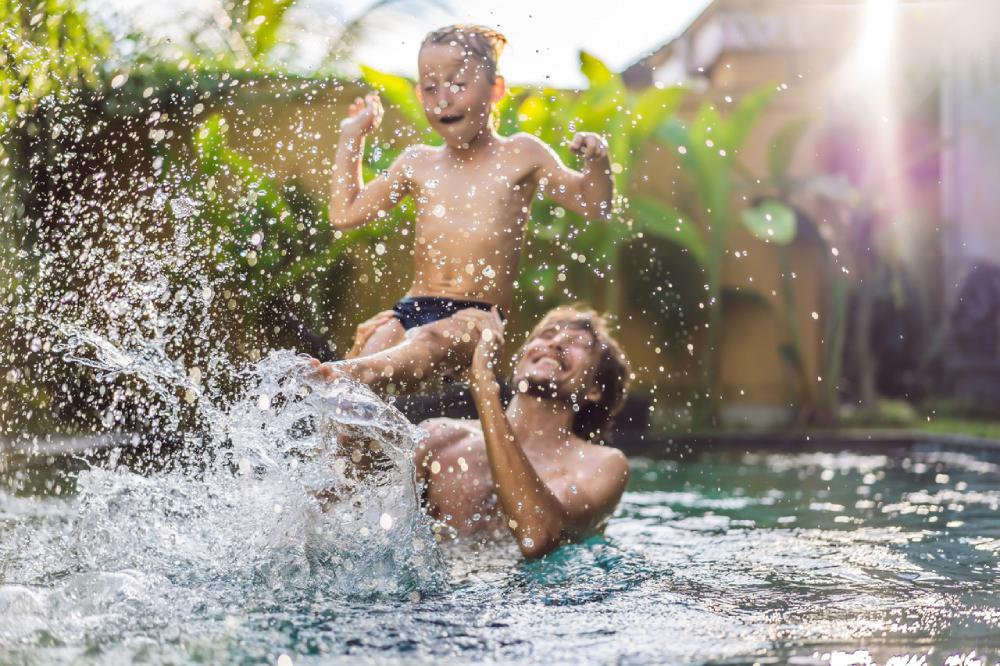 un niño juega con su padre en una piscina