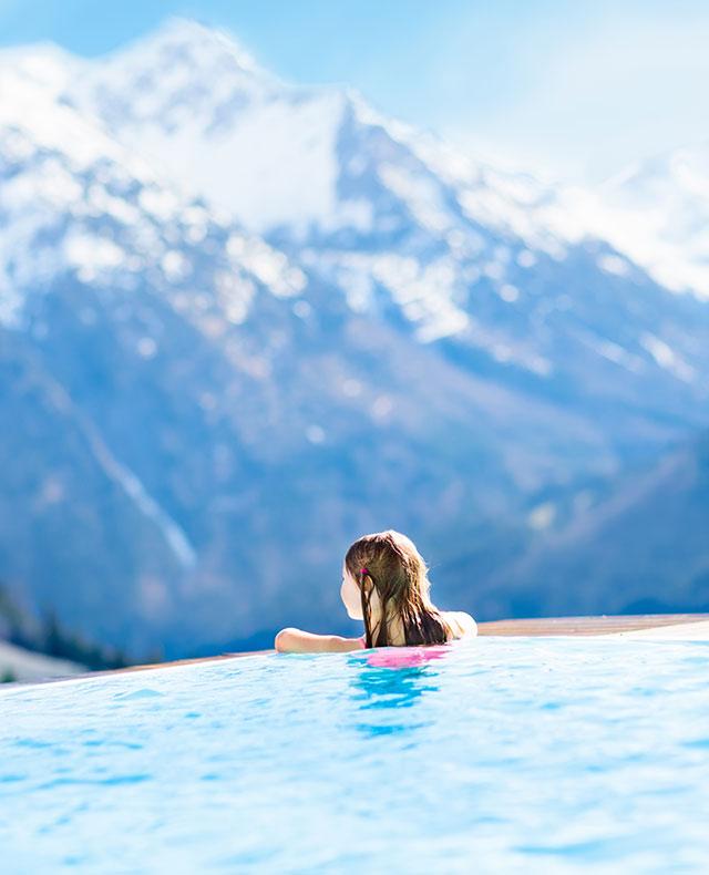fille accoudée à une piscine sur un paysage enneigé