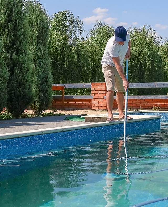 personne en train de nettoyer une piscine