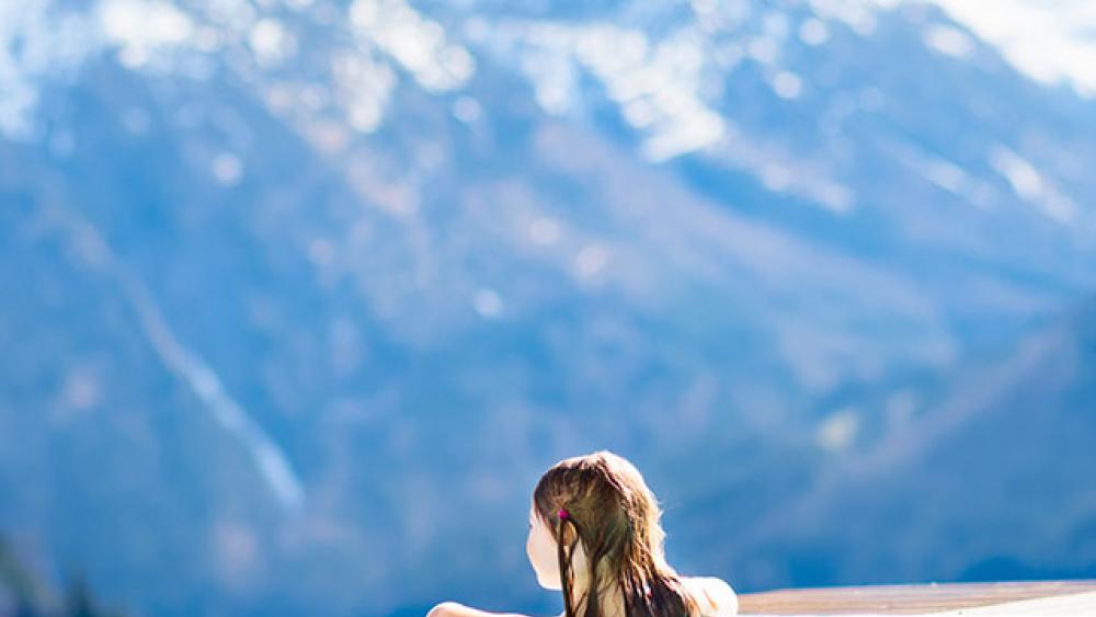 fille accoudée à une piscine sur un paysage enneigé